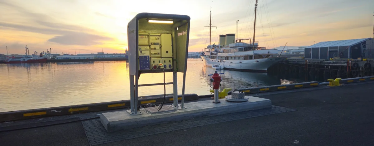 MarinePro pedestal at the edge of the quay with the low sun over the harbour basin and a workboat moored behind.