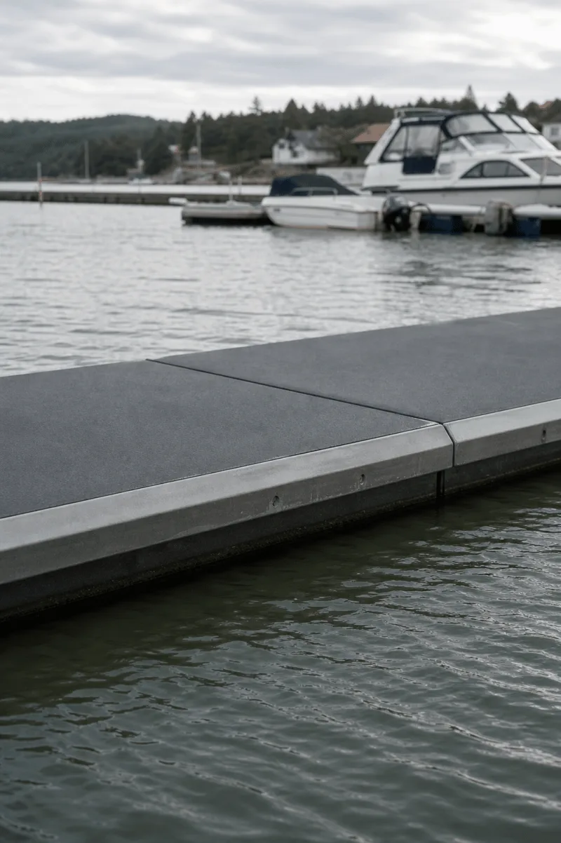 Close view of the Vikingegaarden floating breakwater module joint, textured deck and low grey edge.