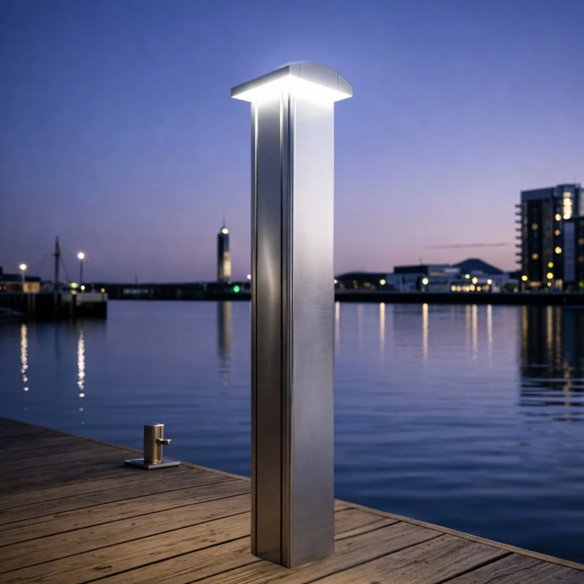 Marinella NEO Light bollard on a wooden pontoon at blue hour, its head lighting the deck with the harbour lights across the water.