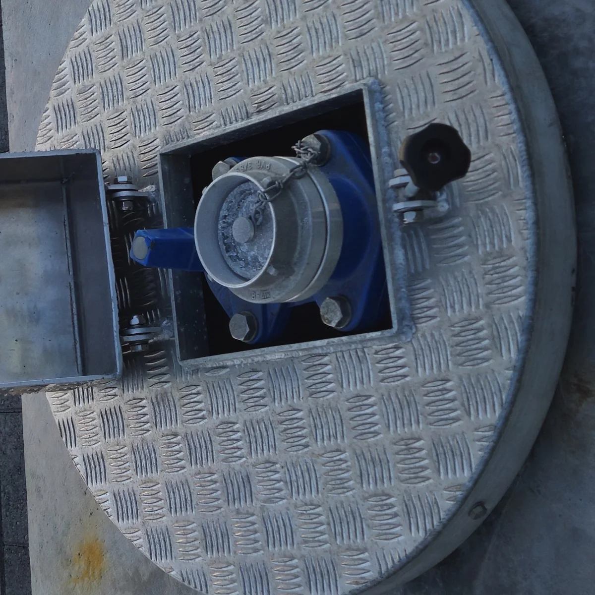 The water coupling inside the flush service point seen from above, with the checker plate cover ring around it.