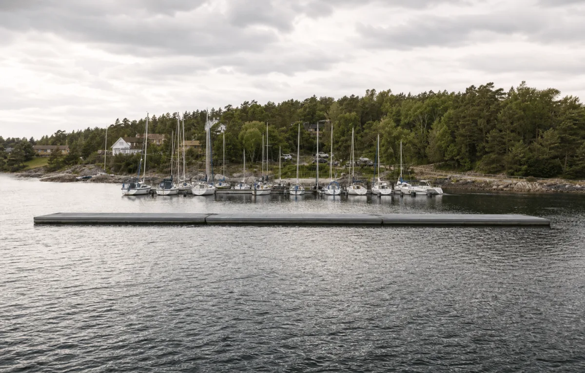 Vikingegaarden floating breakwater spans a Danish marina entrance with sheltered sailboats behind it.