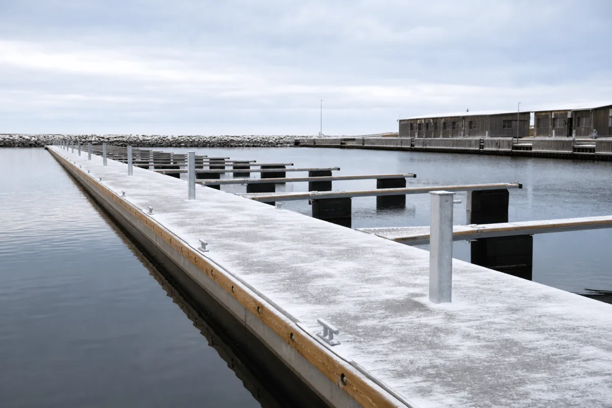 Vikingegaarden concrete pontoons cross an empty winter marina beneath a thin layer of fresh snow.