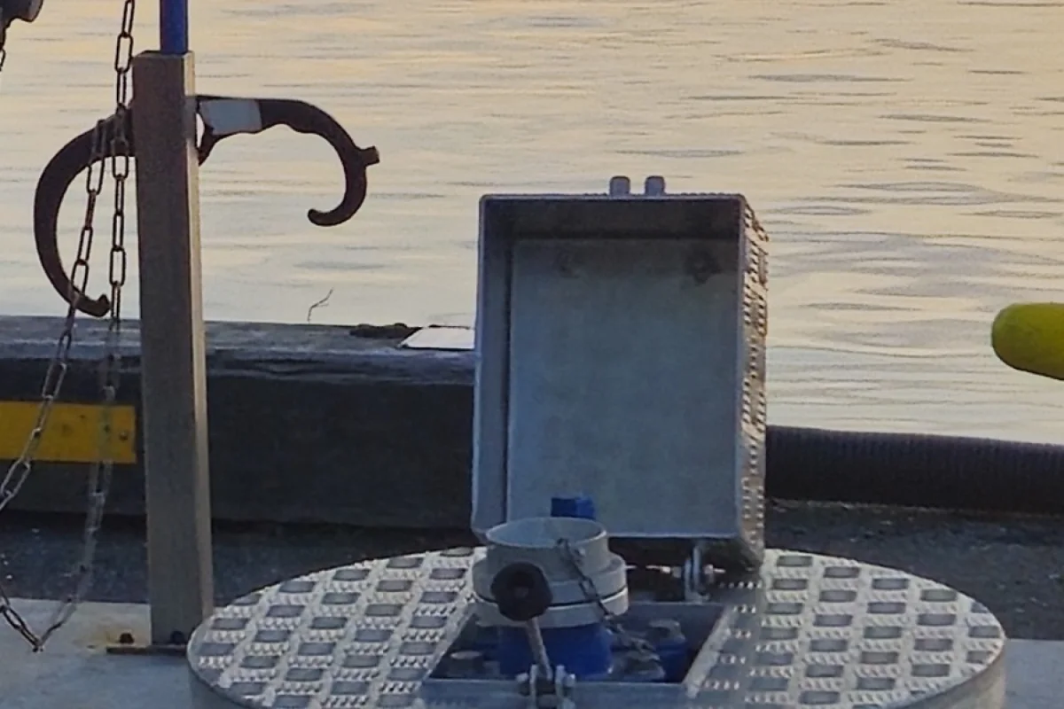 WaterStation-skab: måleskabet i rustfrit stål står åbent på dækslet over servicepunktet, med standrøret og slangeholderen ved siden af.