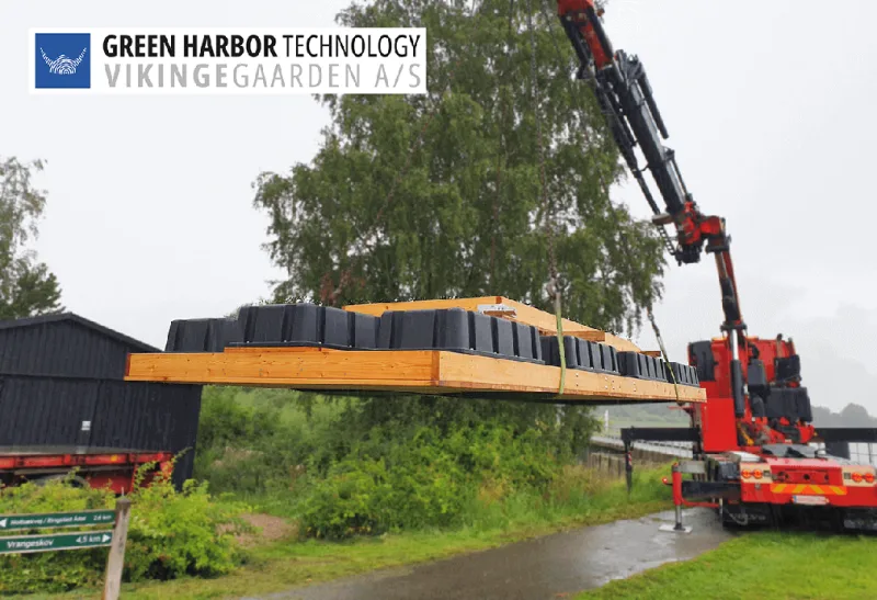 A crane lifting a wooden floating structure beside the lake.