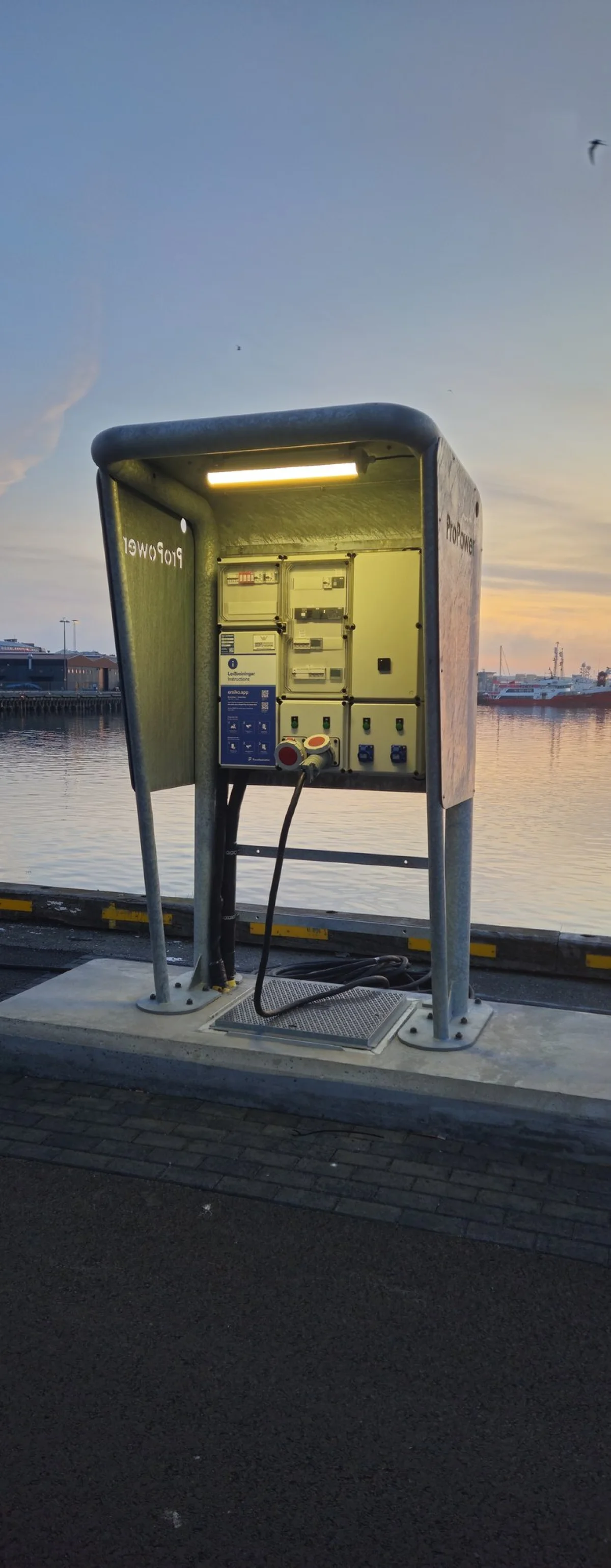 Front view of the MarinePro pedestal, with the lamp under the canopy lighting the panel of sockets and meters.