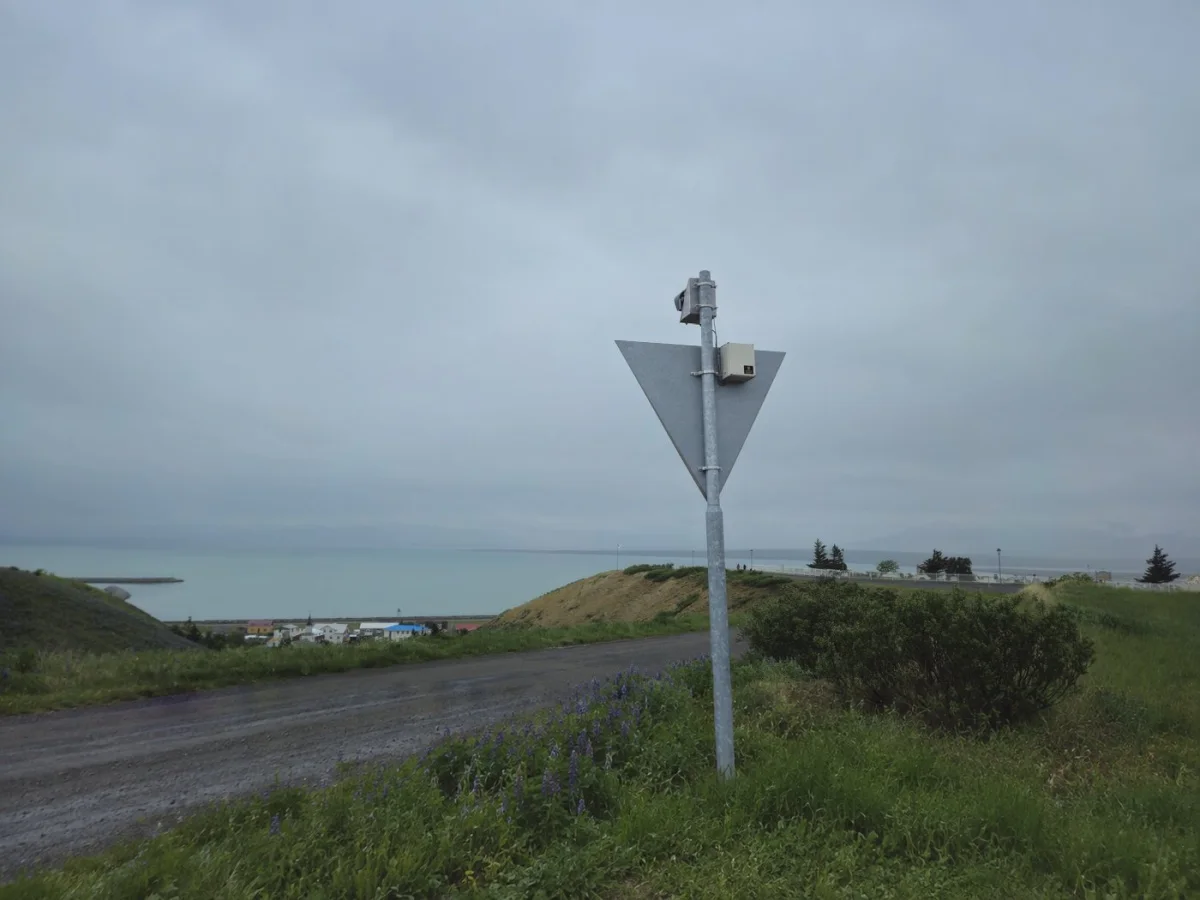 Wide view of the coast with a PowerGuard powered daymark standing against the sea and the hills.