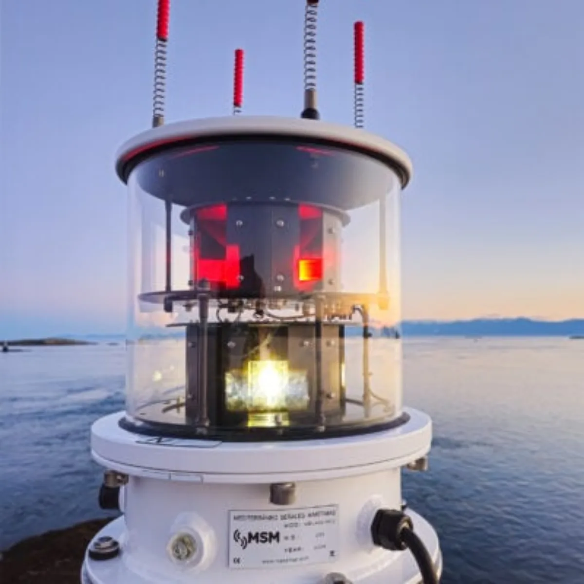 The MBL 400S sector light at dusk: red sector panels and the central lamp inside its glass drum, on a white pedestal.