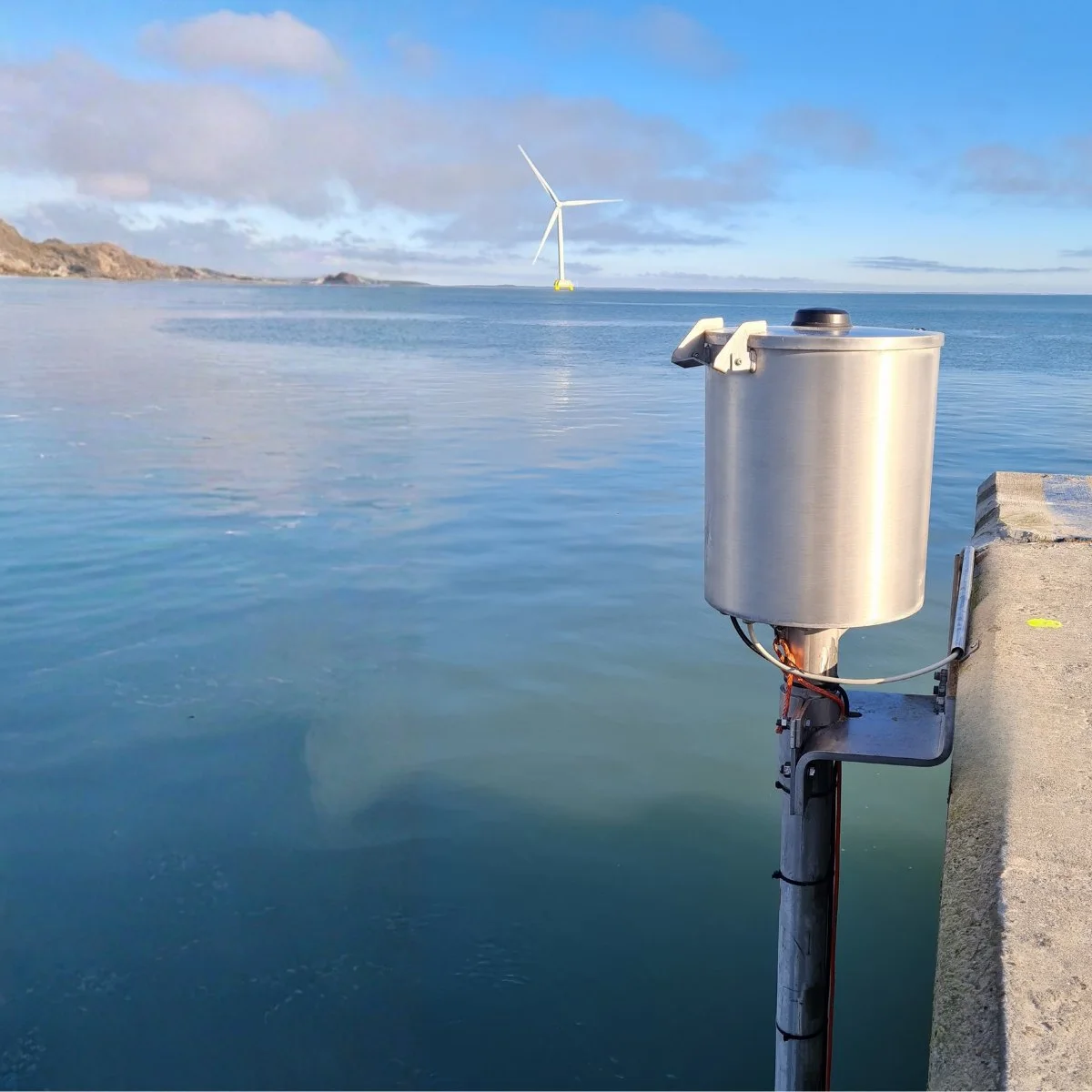 Close view of the OceanWatcher WCM 100 stainless canister clamped to its pole above the water.