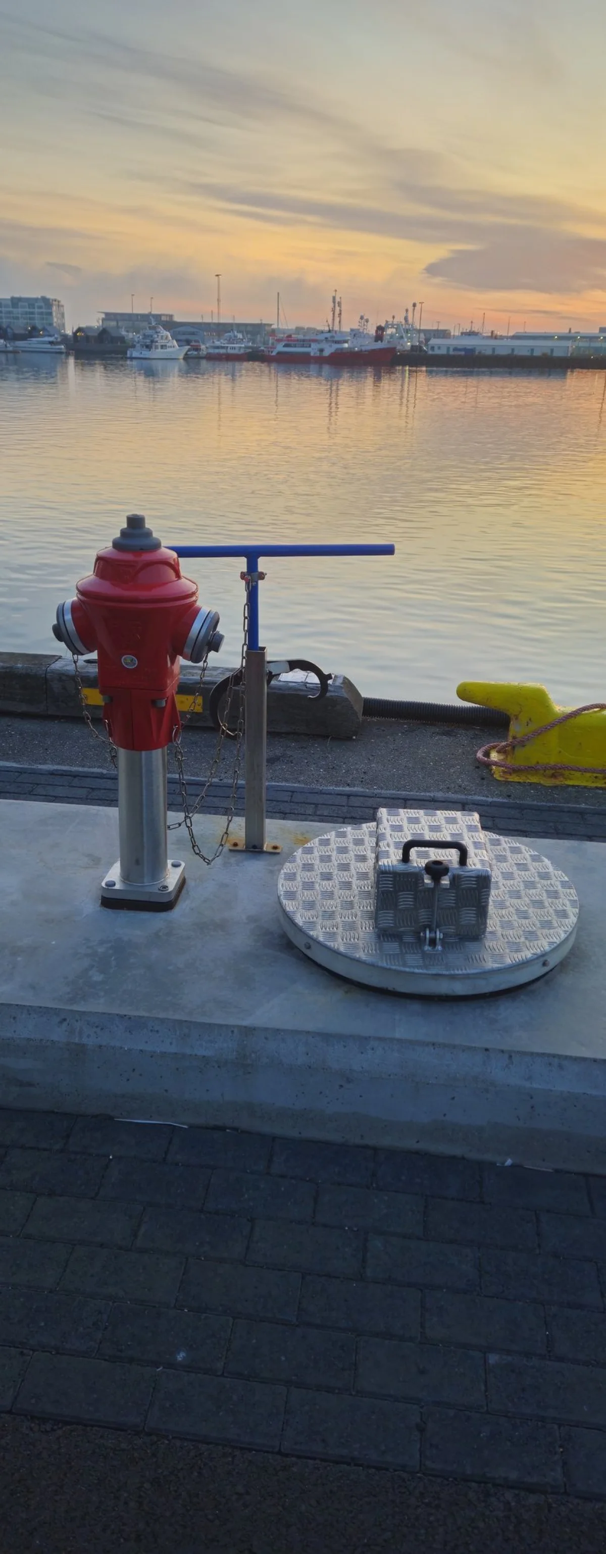 Red water hydrant and the flush service point on the quay at sunset, the water connections that work with the MarinePro pedestal.