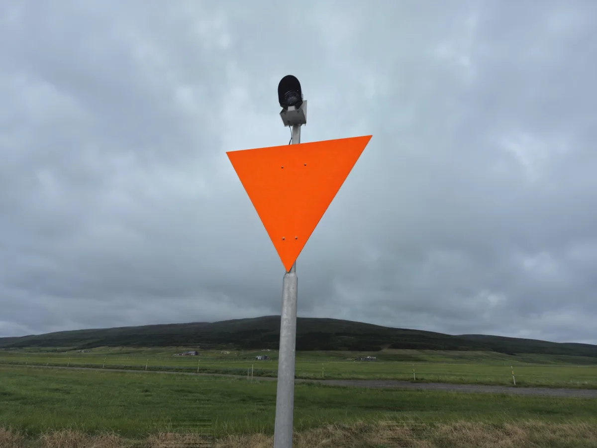Orange triangular daymark on a green hillside, with the light on top supplied by PowerGuard.
