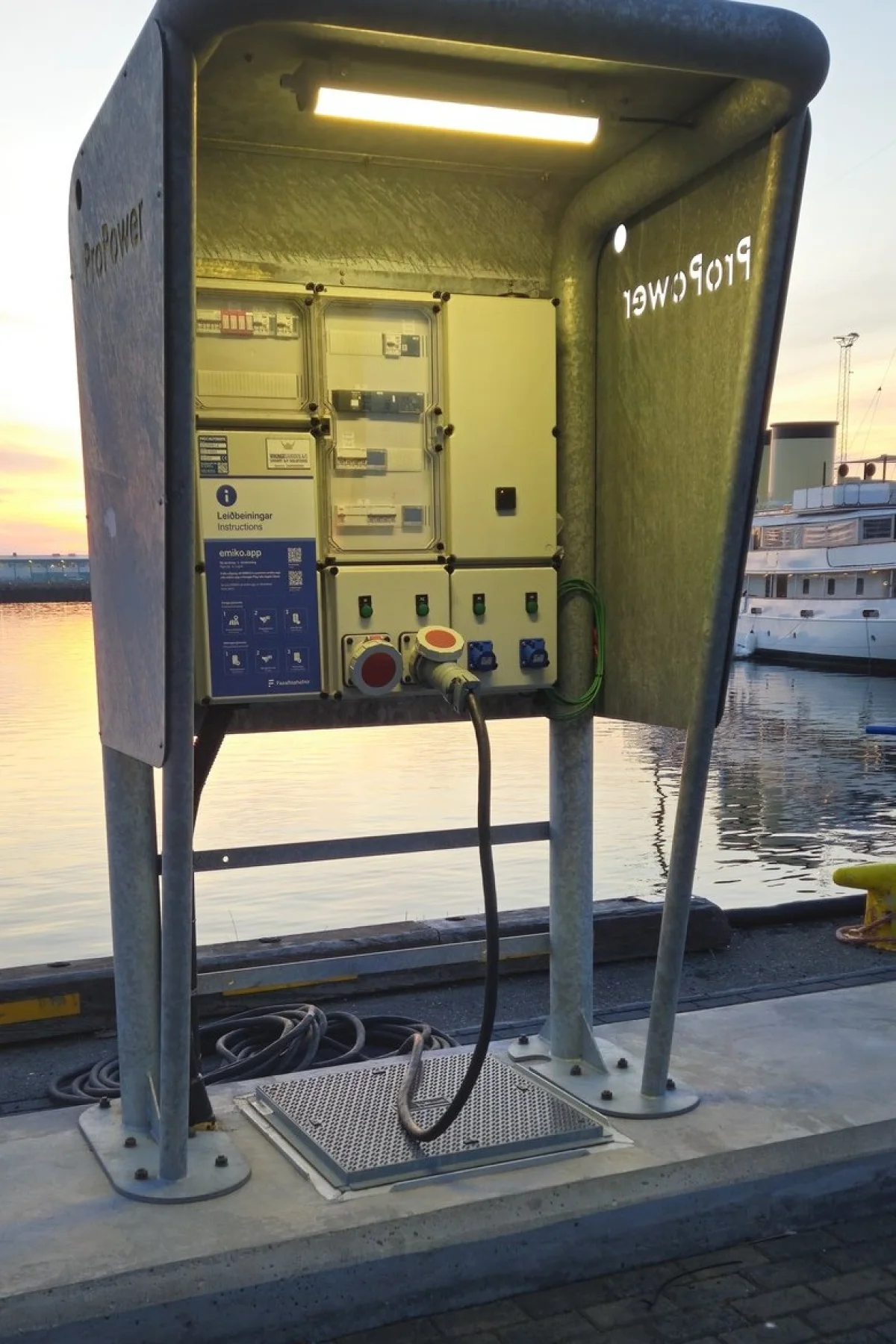 MarinePro pedestal open on the quay with the shore cable connected and a vessel lying alongside in Reykjavik harbour.