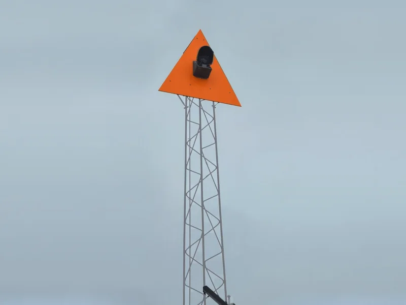 En gittermast med et orange dagmærke og et lys, forsynet uden nettilslutning
